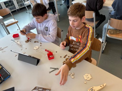 Zwei Jungen sitzen an einem Tisch und basteln mit Lego-ähnlichen Steinen.