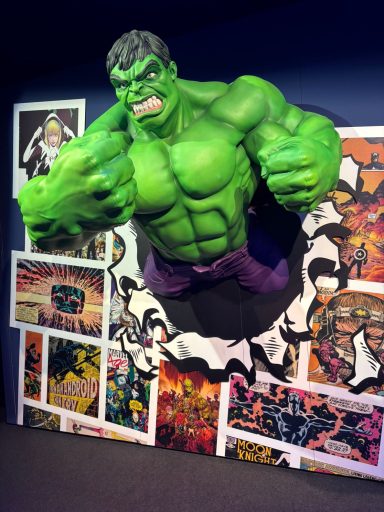 Grüner Hulk-Diorama, durchbricht Wand, umgeben von Comic-Illustrationen.