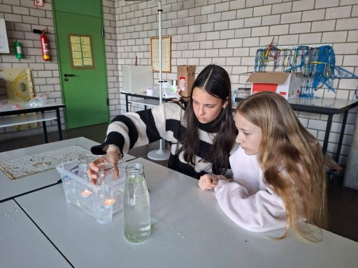 Zwei Mädchen experimentieren mit Wasser und Behältern in einem Klassenzimmer. Zwei Mädchen experimentieren mit Wasser und Behältern in einem Klassenzimmer.