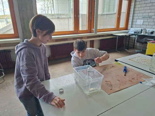 Zwei Kinder experimentieren mit einer Wasserbehälter auf einem Tisch. Zwei Kinder experimentieren mit einer Wasserbehälter auf einem Tisch.