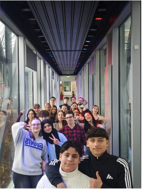 Gruppenzusammenkunft von Jugendlichen in einem modernen Gang, lächelnd und posierend.